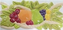 handmade ceramic tile with a high relief fruit design and a multi-colored glaze